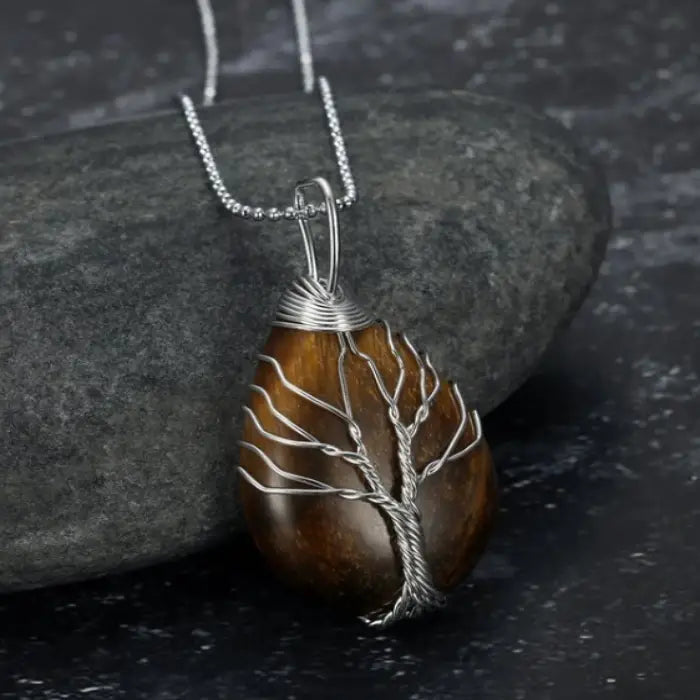 Tiger eye teardrop gemstone pendant with silver wire tree of life design on silver chain and stone.