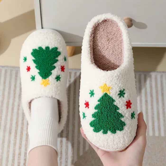 White Christmas slippers with a green Christmas tree design and colorful star accents.