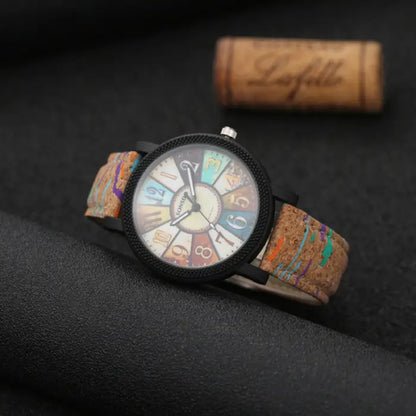 Trendy analog wristwatch with cork band and multicolor dial, photographed on a dark background for contrast.