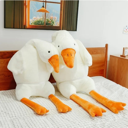 Two large white duck plush toys sitting on bedroom floor.