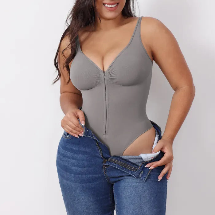 V neck shapewear bodysuit in grey shown while putting on jeans, emphasizing smooth shaping compression and supportive everyday contouring