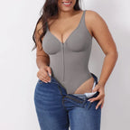V neck shapewear bodysuit in grey shown while putting on jeans, emphasizing smooth shaping compression and supportive everyday contouring