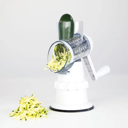 Fresh zucchini being spiralized on a white manual vegetable cutter on a plain background.