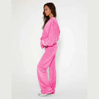 Velour tracksuit in pink side view featuring plush hoodie and flowing pants for flattering fit and off duty comfort