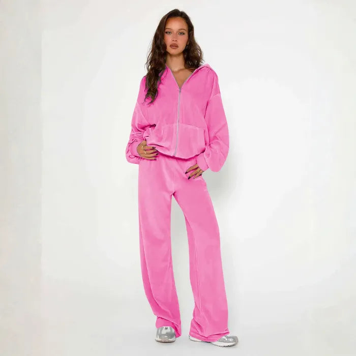 Velour tracksuit shown in soft pink featuring a relaxed hoodie and wide leg pants for plush comfort and modern street style