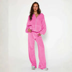 Velour tracksuit shown in soft pink featuring a relaxed hoodie and wide leg pants for plush comfort and modern street style