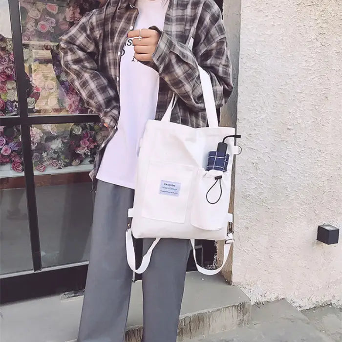 White canvas tote with front pockets modeled with casual street style outfit