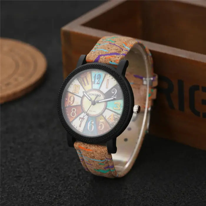 Vintage-style analog wristwatch with a cork band and colorful dial, placed near a wooden box for aesthetics.