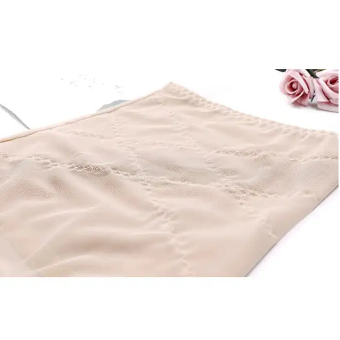 Waist cincher shapewear laid flat on white surface with rose decor background
