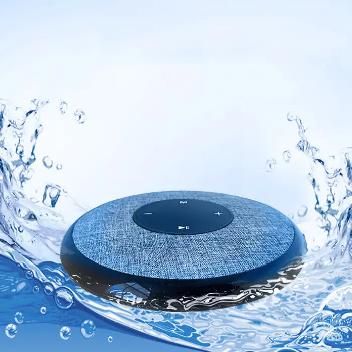 Circular smart speaker with fabric cover surrounded by water splashes, demonstrating its waterproof capabilities