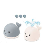 Whale bath toy in gray and white showing water spray feature with splash icons.