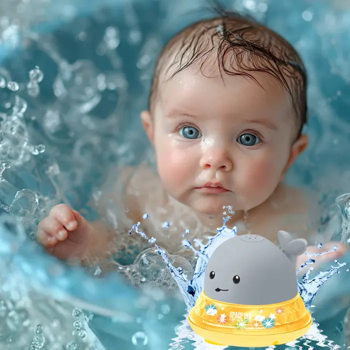 Whale bath toy spraying water beside baby with glowing lights in a tub.