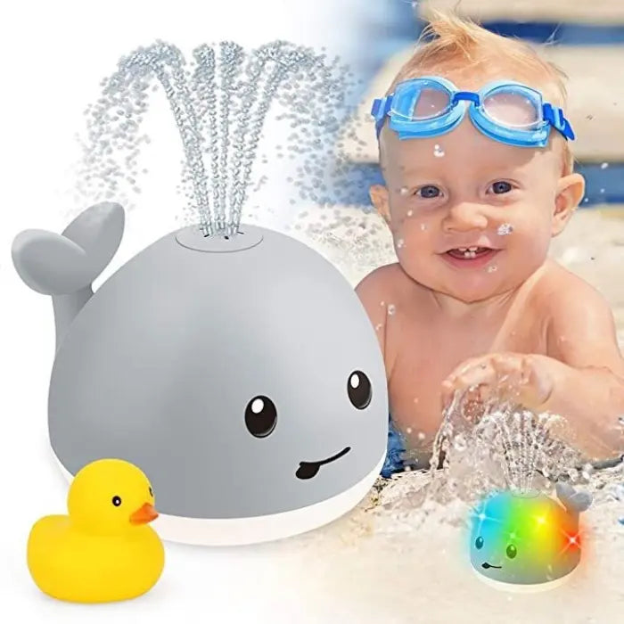 Smiling baby playing with large whale bath toy spraying water near swimming pool.