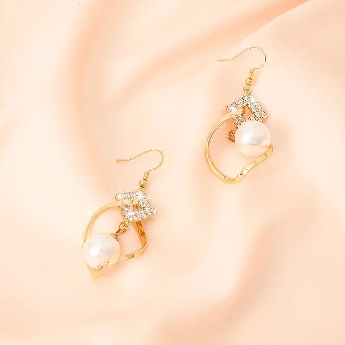 White bead earrings with gold twist design and crystal embellishments for timeless fashion jewelry.