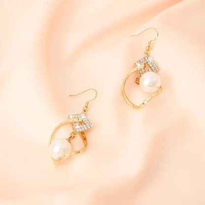 White bead earrings with gold twist design and crystal embellishments for timeless fashion jewelry.