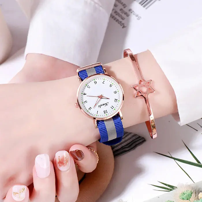 Women's watch with a white dial and blue strap, styled with a rose gold star bracelet.