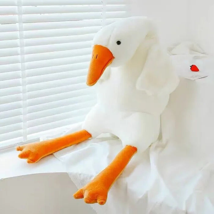 White duck plush toy positioned on a window sill looking outside.