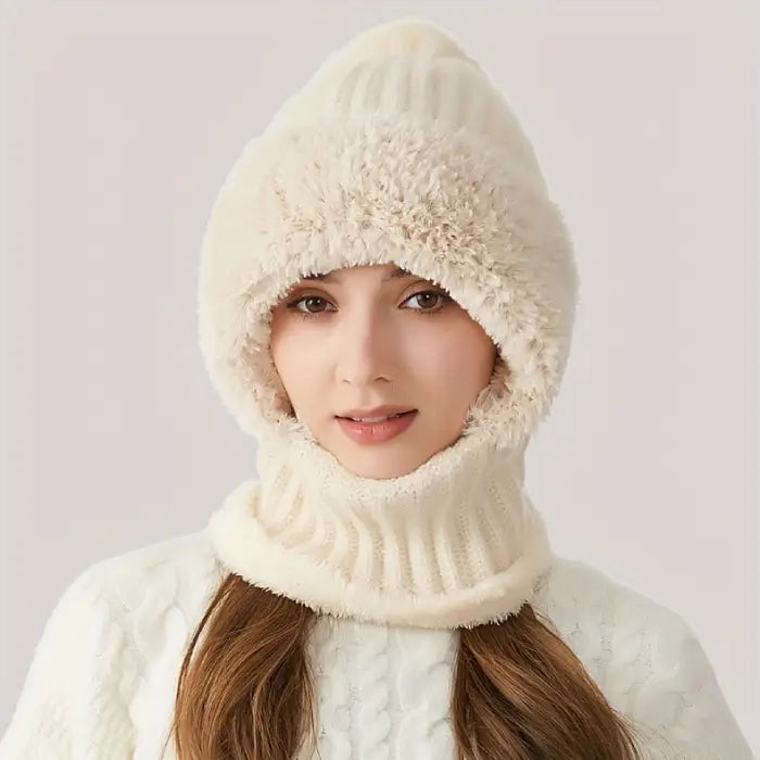 Person wearing a fluffy white faux fur hat with knit trim and a pom pom on top