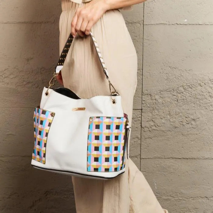 White shoulder bag with retro geometric panels styled with flowing beige dress, showing versatile wear