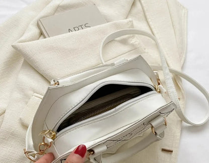 Open white handbag showing interior capacity, gold zipper, and strap on cream fabric background