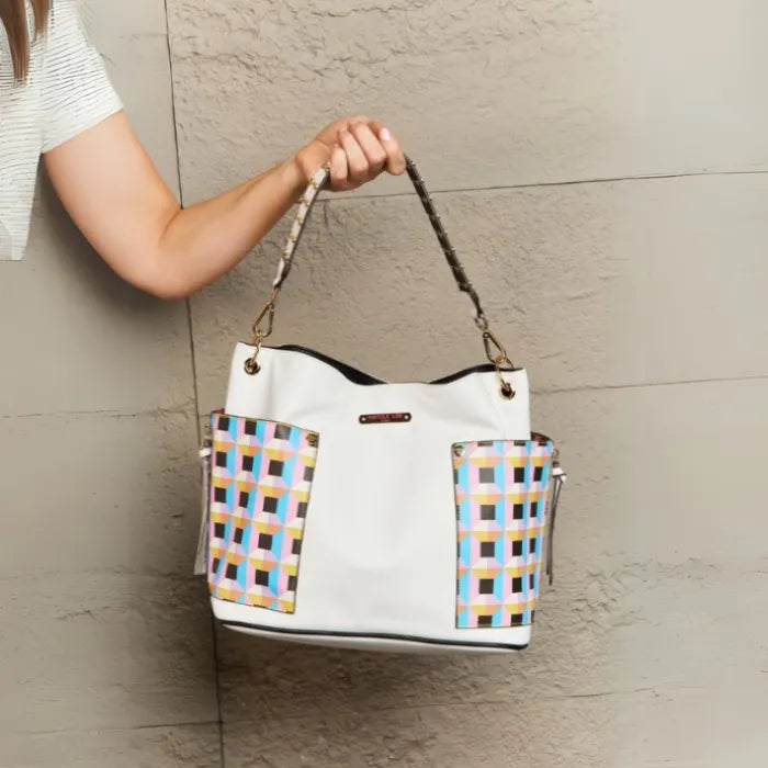 White pebbled leather tote with colorful checkered side panels and gold hardware, showing spacious main compartment