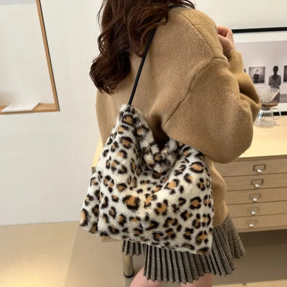 White leopard print faux fur handbag worn on the shoulder with a black strap for a trendy outfit.