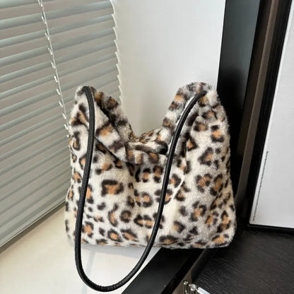 White leopard print faux fur handbag with a black strap displayed elegantly on a modern shelf.