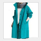 Windbreaker Trench Coat in bright teal with black buttons styled with scarf and white shirt.