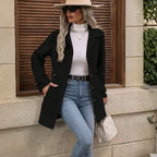 winter-belted-peacoat black coat paired with jeans and hat in a modern streetwear outfit