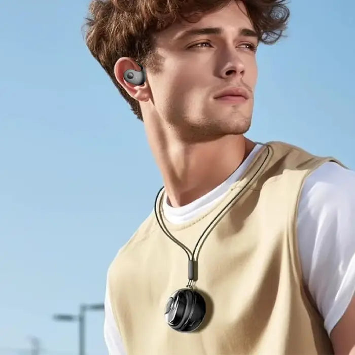 Wireless earbud worn in ear against blue sky background, shown with beige vest and white t-shirt