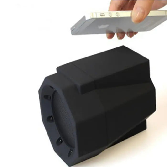 Black octagonal wireless induction speaker with smartphone placed on top for audio amplification