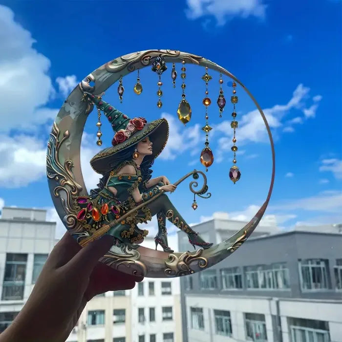 Hand holding crystal moon witch suncatcher window decoration outdoors against urban building background and blue sky