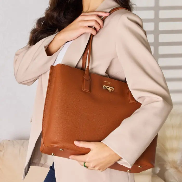 Woman carrying brown leather tote bag over shoulder, wearing beige coat, highlighting bag's versatility and elegance