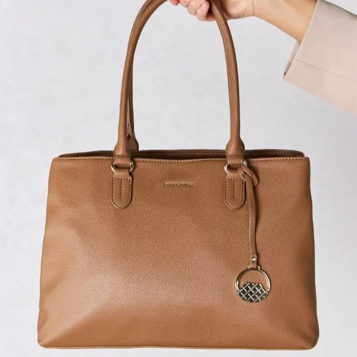  Woman holds stylish brown leather handbag, perfect accessory for outfits.