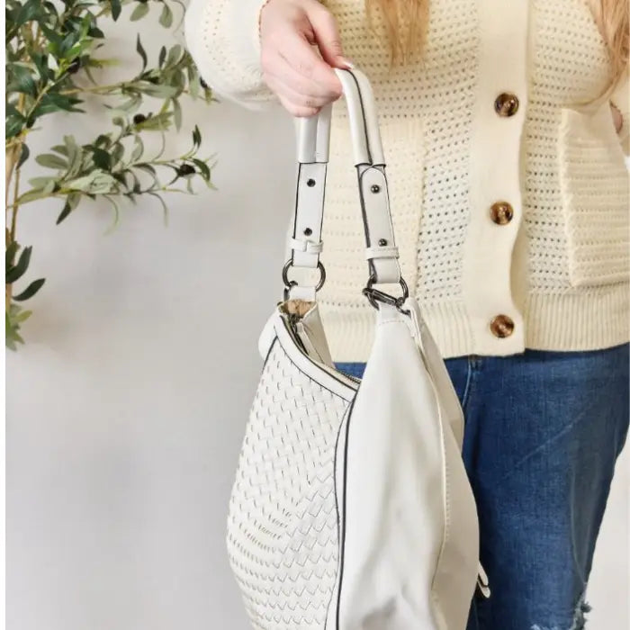 Woman in cream sweater holding a stylish white woven handbag, perfect for daily use.