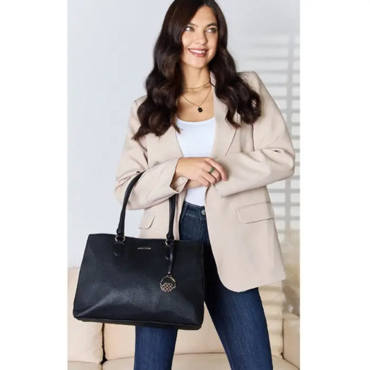 Stylish woman in beige jacket holding a black designer handbag.