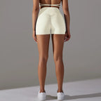 Womans yoga shorts in cream with ruched back detail and high rise fit, shown from behind.