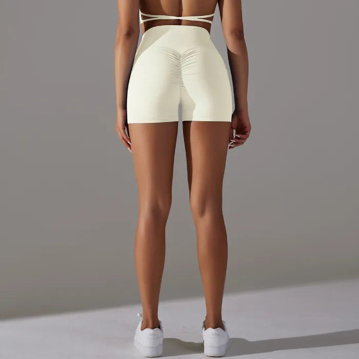 Womans yoga shorts in cream with ruched back detail and high rise fit, shown from behind.