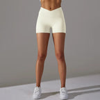 Womans yoga shorts in soft cream tone with crossover waistband, modeled from front view.