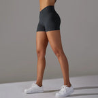 Womans yoga shorts in dark grey featuring side pocket and high waist shown from angled side view.