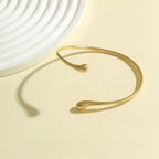 women gold open end arm cuff bracelet displayed on neutral background