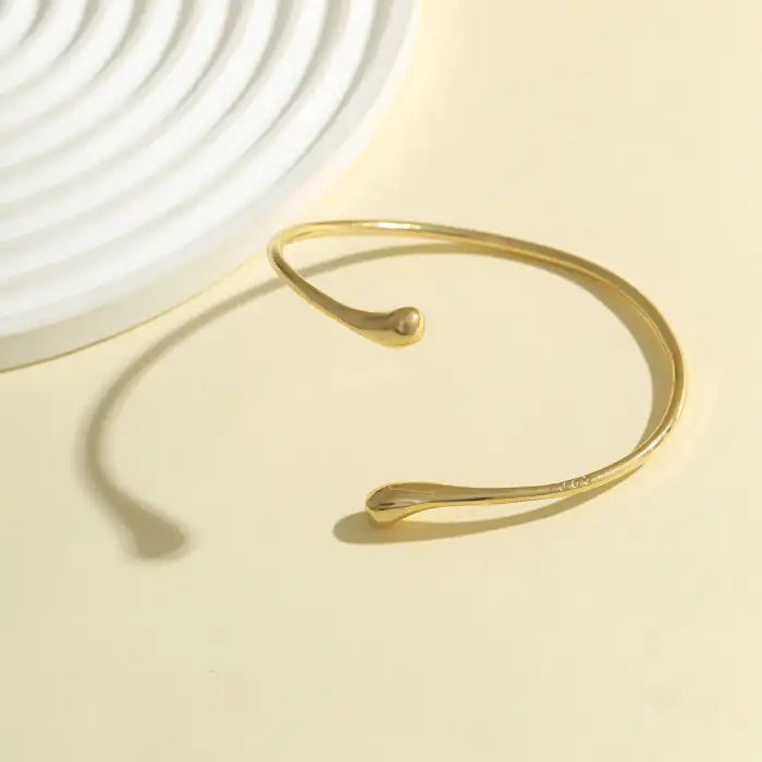 women gold open end arm cuff bracelet displayed on neutral background