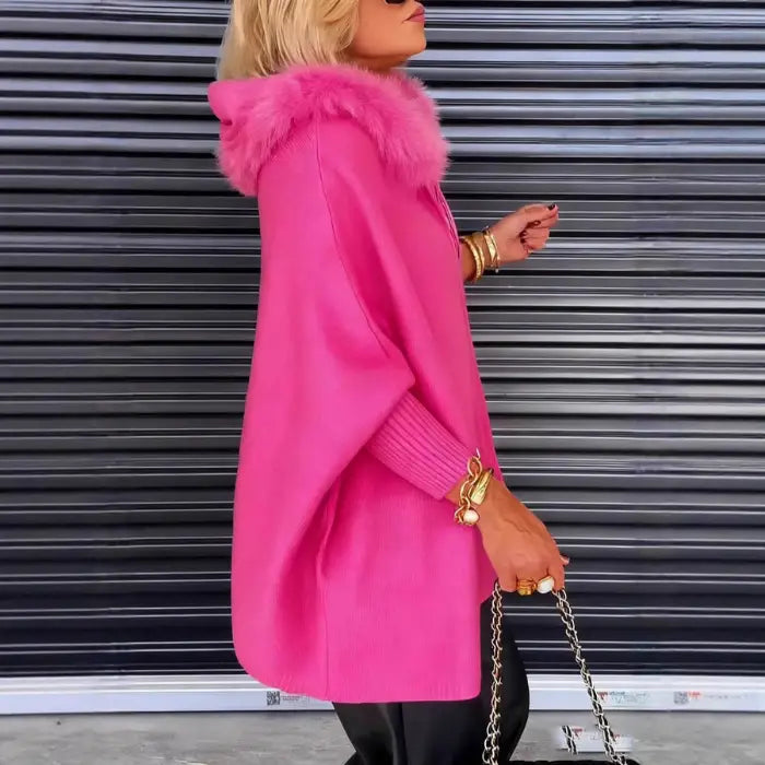 Women’s cape coat in bright pink shown from side profile, fur hood and draped silhouette offering warm luxurious winter outerwear style