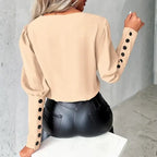 womens contrast v neck long sleeve blouse black trim back view in beige highlighting elegant sleeve buttons and a classic neutral style