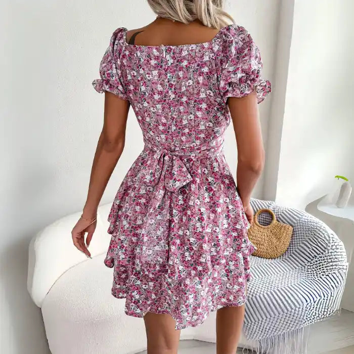  Women's flower print mini dress in pink back view featuring tied waist and puffed short sleeves.