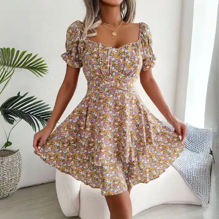 Women’s flower print mini dress with flared hemline and smocked waist shown in soft yellow floral print.