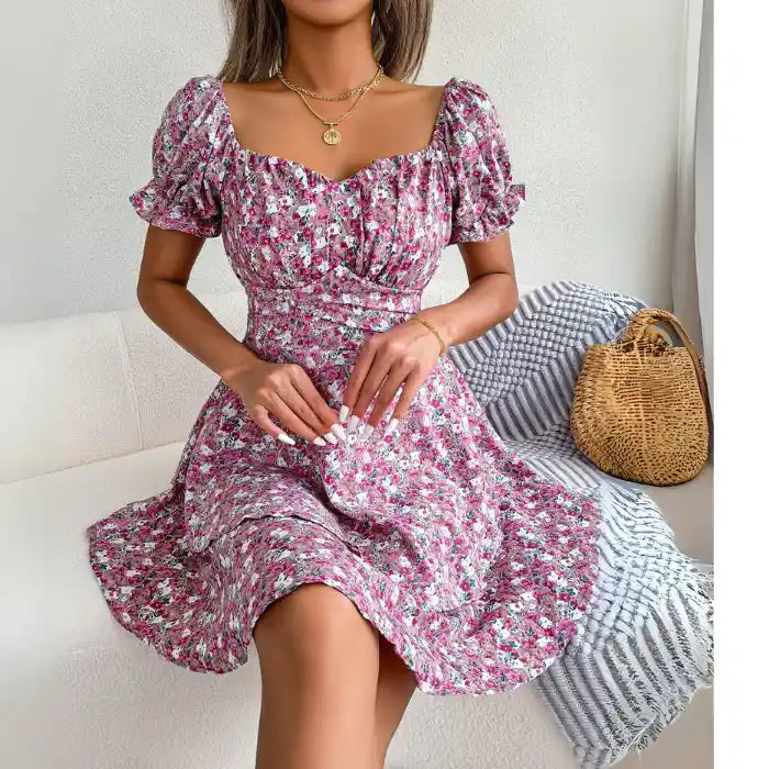 Women's flower print mini dress in pink with puff sleeves and sweetheart neckline while seated.