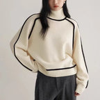 Classic ivory Women's Half Turtleneck Sweater with black trim, styled with wide-leg charcoal trousers.