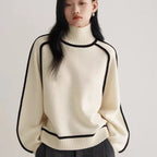 Women's Half Turtleneck Sweater in ivory with black trim, relaxed fit, styled with grey trousers.