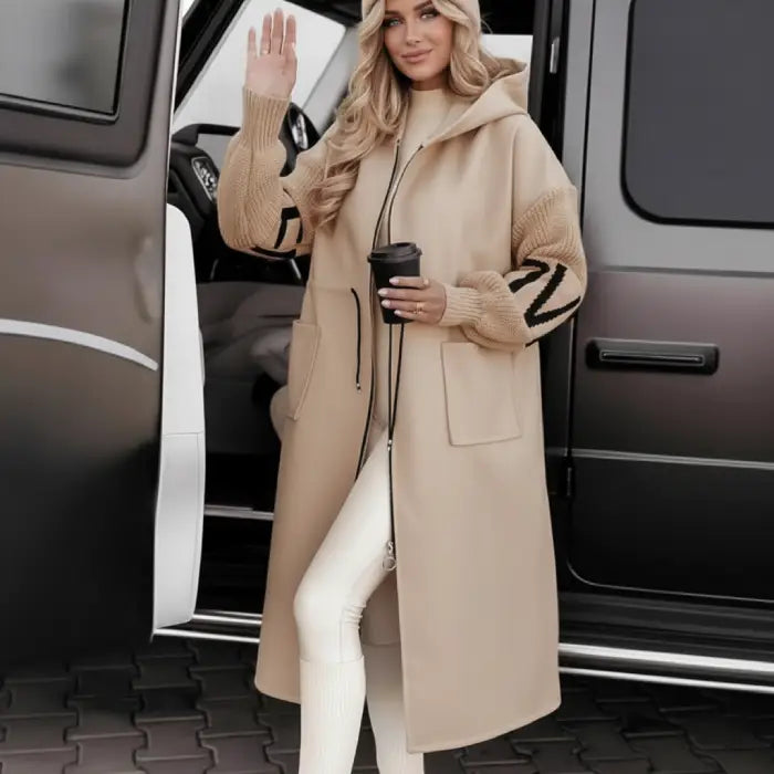 Women’s long hooded cardigan coat in beige worn beside vehicle, cozy knit sleeves adding warm luxury comfort for stylish winter streetwear
